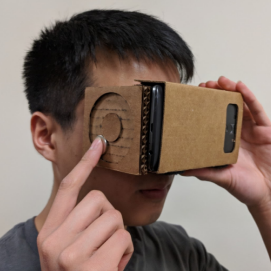 Person holding up Google Cardboard interacting with an attached interface on the side
